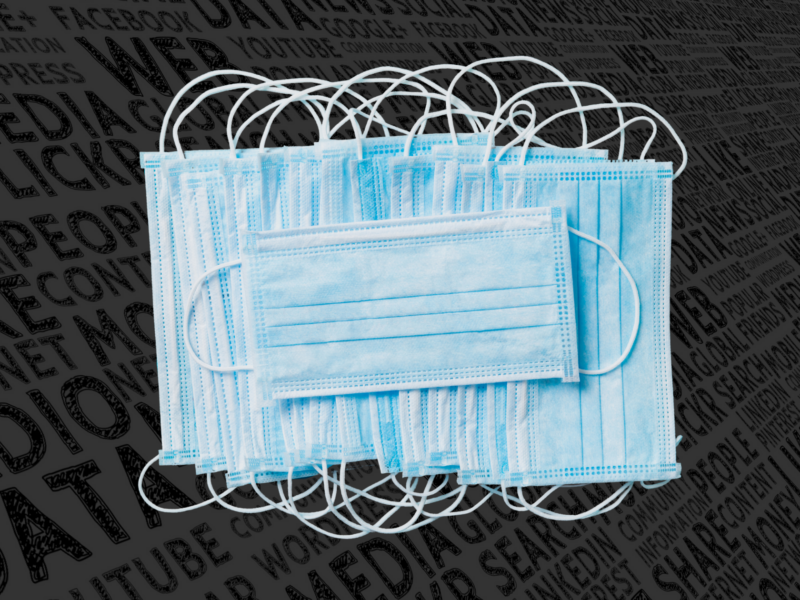 The image shows a pile of blue surgical masks overlapping each other, with their white ear loops tangled together. The background consists of various words related to media and technology, such as "WEB," "SOCIAL MEDIA," "GOOGLE," "YOUTUBE," and others, in a dark grey color.