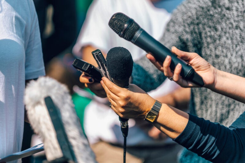 Journalists holding microphone and dictaphone, interviewing speaker.