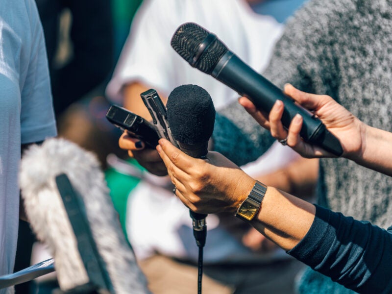 Journalists holding microphone and dictaphone, interviewing speaker.