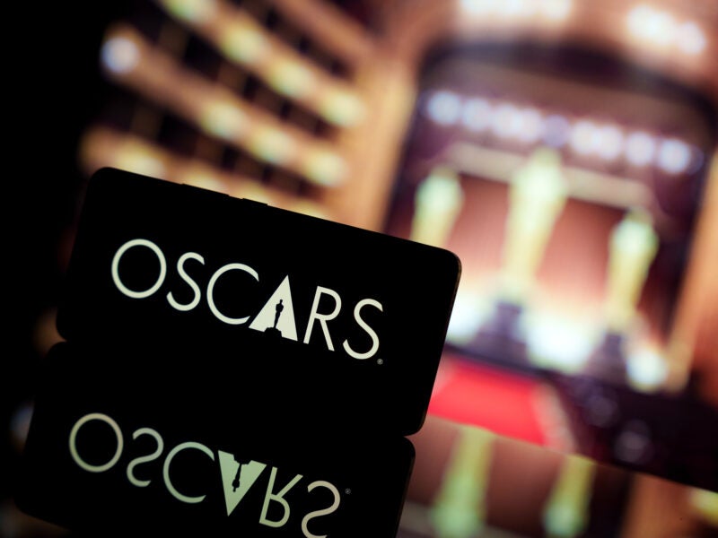 A smartphone displaying the Oscars logo against a blurred awards ceremony background. January 13, 2025
