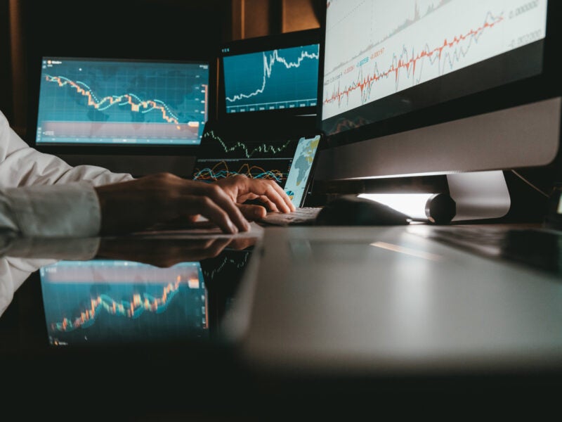 Close-up of male trader typing on computer keyboard while trading on stock market in night office