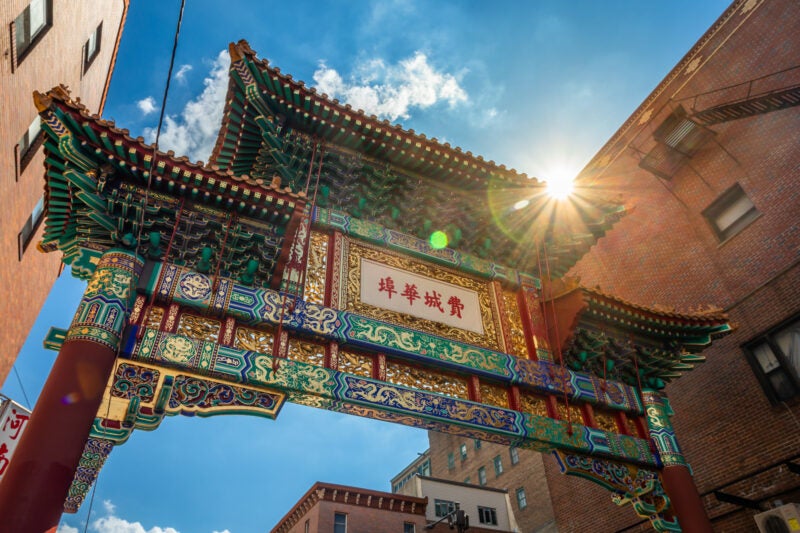 Vibrant and colorful Entrace Gate to Chinatown shot at an angle in Philadelphia, PA, USA, on a sunny Day - Backlight from Sun with Lens Flare; Letters translate "Philadelphia Chinatown"