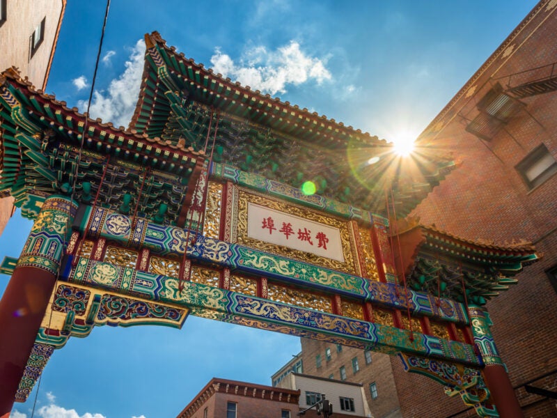 Vibrant and colorful Entrace Gate to Chinatown shot at an angle in Philadelphia, PA, USA, on a sunny Day - Backlight from Sun with Lens Flare; Letters translate "Philadelphia Chinatown"