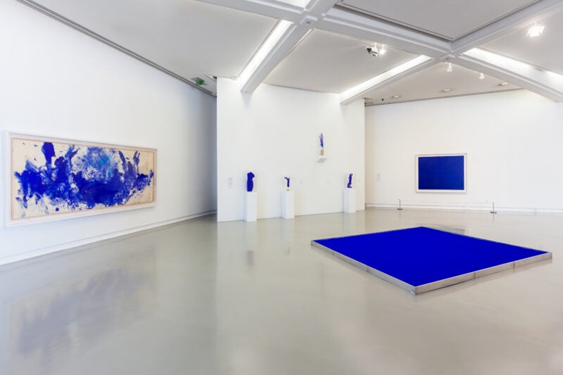 Stock image of an art gallery with blue highlights on each art work. Image is abstract.