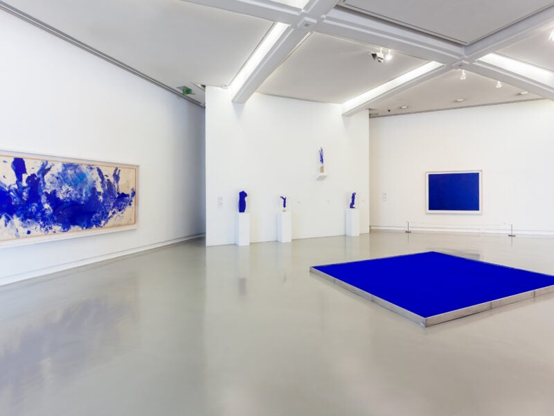 Stock image of an art gallery with blue highlights on each art work. Image is abstract.